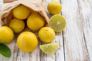 limones recién hechos en una bolsa de papel sobre una mesa de madera blanca foto