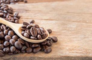Coffee beans in wooden spoon on wooden background photo