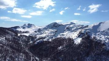 Aerial drone of an amazing panoramic view of a mountain range covered with snow during a sunny day. Winter season and holidays in the mountains. Blue sky and white vibrant colors. Cinematic shot. video