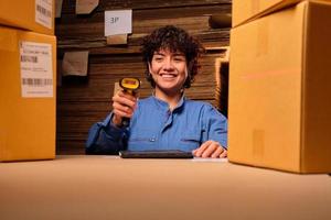 One female worker in safety uniform uses a bar code scanner and tablet to check shipping orders at parcels warehouse, paper manufacture factory for the packing industry, logistic transport service. photo