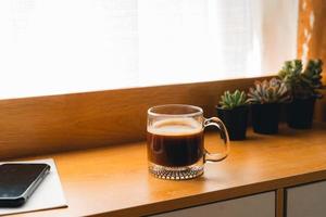 café por la mañana, café en una taza sobre una mesa de madera con un cuaderno foto