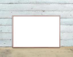 la maqueta de marco horizontal de oro rosa a4 se encuentra sobre una mesa de madera sobre un fondo de madera pintada de blanco. estilo rústico, belleza sencilla. 3 renderizar. foto