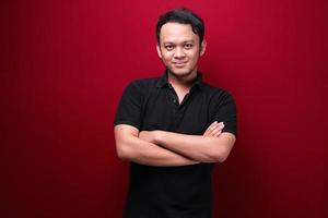 Portrait of smiling young asian man wearing black shirt isolated on red. photo