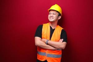 Portrait of smiling young asian man worker isolated on red. photo