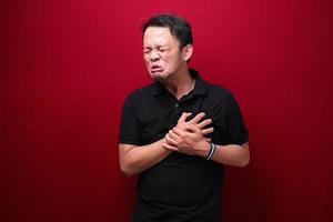 ataque al corazón o corazón roto de un joven asiático con emoción dolida usa camisa negra. foto
