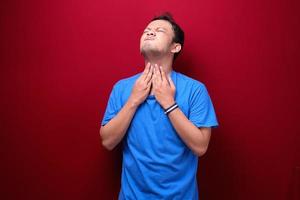 Sore throat of young asian man in red background photo