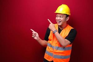 Smile and happy young asian man worker is with with hand point on empty space photo
