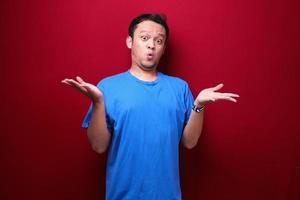 Young asian man is surprised and shouting wow with pointing right with his hand isolated on red background. photo