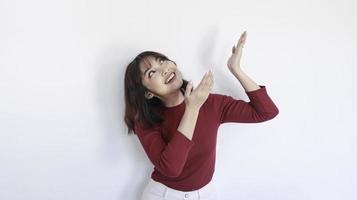 feliz apuntando arriba de una hermosa chica asiática con camisa roja de fondo blanco