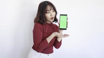 impactar a una hermosa chica asiática en un teléfono de pantalla verde con fondo blanco