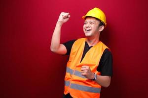 Happy excited and smiling young Asian man worker raising his arm up to celebrate success or achievement. photo