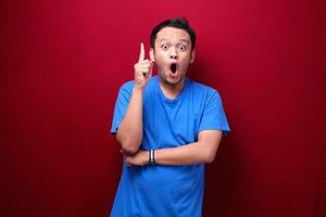 Shock Young asian man is surprised and shouting wow with pointing above with his hand isolated on red background. photo