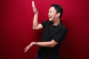 Smile and happy young asian man is with hand point on empty space photo