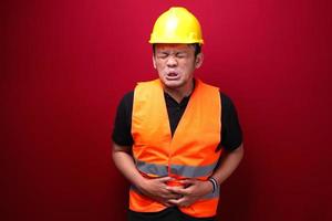 Upset young asian man worker with serious stomach ache photo