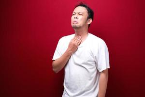 Sore throat of young asian man in red background photo