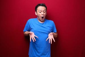 Wow Young asian man is surprised and shouting with pointing bottom with his hand on red background. photo