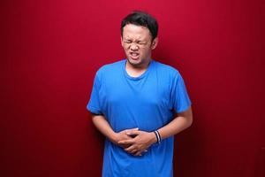 Upset young asian man with serious stomach ache photo