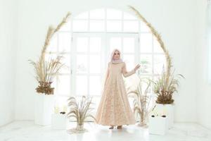 Retrato de cuerpo entero de dama con vestido de novia, maquillaje de boda en hijab. vestido de novia malayo o indonesia, concepto de belleza o eidul fitri. Hermosa mujer musulmana del sudeste asiático posando en traje de islam foto