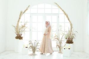 Retrato de cuerpo entero de dama con vestido de novia, maquillaje de boda en hijab. vestido de novia malayo o indonesia, concepto de belleza o eidul fitri. Hermosa mujer musulmana del sudeste asiático posando en traje de islam foto