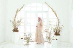 Retrato de cuerpo entero de dama con vestido de novia, maquillaje de boda en hijab. vestido de novia malayo o indonesia, concepto de belleza o eidul fitri. Hermosa mujer musulmana del sudeste asiático posando en traje de islam foto