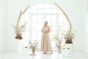 Retrato de cuerpo entero de dama con vestido de novia, maquillaje de boda en hijab. vestido de novia malayo o indonesia, concepto de belleza o eidul fitri. Hermosa mujer musulmana del sudeste asiático posando en traje de islam foto