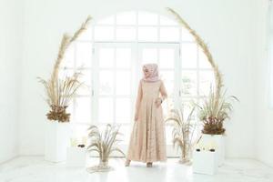 Retrato de cuerpo entero de dama con vestido de novia, maquillaje de boda en hijab. vestido de novia malayo o indonesia, concepto de belleza o eidul fitri. Hermosa mujer musulmana del sudeste asiático posando en traje de islam foto