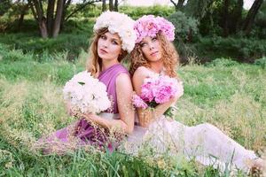 two caucasian beautiful woman with a wreath of pink peonies. Spring, blossom, fairy concept photo