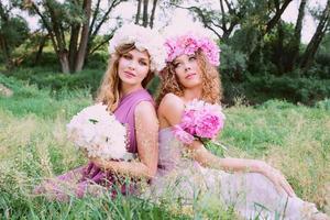 dos hermosas mujeres caucásicas con una corona de peonías rosas. primavera, flor, concepto de hadas foto