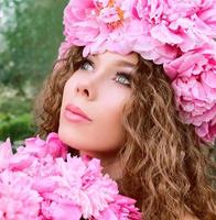 hermosa mujer caucásica con una corona de peonías rosas en la cabeza. primavera, flor, concepto de hadas foto