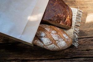 different bread rye and baguette in bag isolated on wood photo