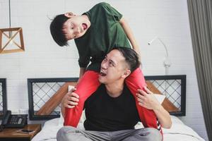 Portrait of happy father giving son piggyback ride on his shoulders and looking up photo