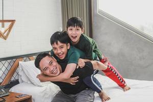 hijos felices abrazando a su padre en el dormitorio foto