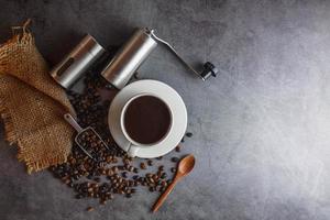 Hand coffee grinder and coffee beans and coffee cup on table. photo