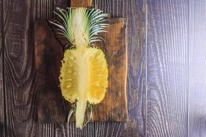 Fresh pineapple fruit cut in half on a wooden table photo