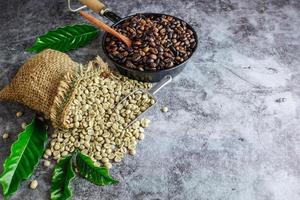 Raw green unroasted coffee beans in brown sacks and roasted coffee beans in a pan. photo