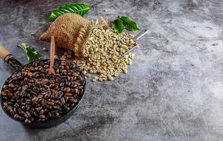 Raw green unroasted coffee beans in brown sacks and roasted coffee beans in a pan. photo