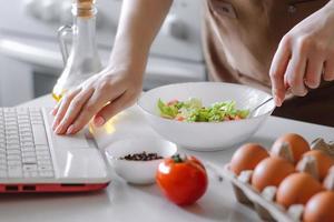 mujer preparando una ensalada de dieta usando un libro de cocina digital. foto