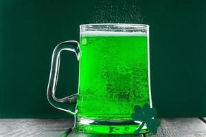 celebrando st. día de San Patricio. vaso de cerveza verde con espuma. foto