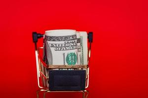 American dollar exchange rate. Dollars in a shopping cart on a red background. photo