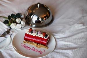 Romantic birthday cake with white rose on the bed photo