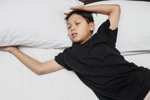 Asian boy sleeping soundly on the bed photo