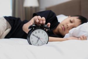 Alarm clock showing 7 o'clock for wake up time with blurry background of boy sleeping on the bed photo