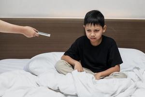 niño asiático llorando cuando su teléfono inteligente tomado por mamá foto