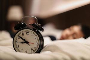 Alarm clock showing 9 o'clock pm with blurry background of boy sleeping on the bed photo