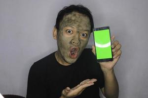 Shock Asian Man showing blank screen when he use beauty face mask photo