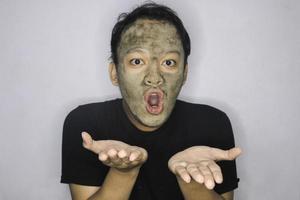 Smile Asian Man pointing in hand when he use beauty face mask photo