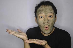 Smile Asian Man pointing in hand when he use beauty face mask photo