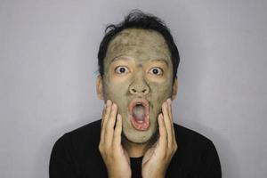 wow, el hombre asiático se sorprendió y miró a la cámara cuando usó una máscara facial de belleza foto