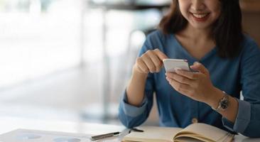 Mujer asiática de negocios con smartphone para hacer finanzas matemáticas en un escritorio de madera en la oficina, impuestos, contabilidad, concepto financiero foto