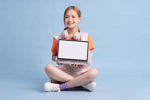 Young Asian student posing on blue background photo